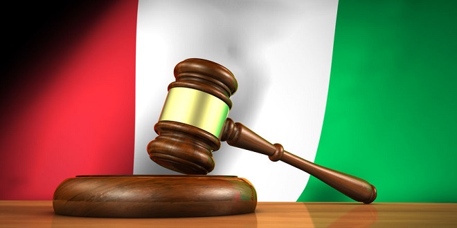 BetConstruct - Law and justice in Italy concept with a 3d rendering of a gavel on a wooden desktop and the Italian flag on background.