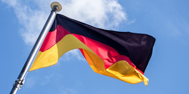 mybet - German flag fluttering in the wind against the blue sky with light clouds, diagonal view from below, soft motion blur