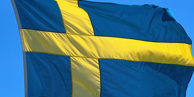 virtual sports - 01.06.2020, Schleswig, the Swedish flag with the yellow Scandinavian cross on a blue background, illuminated by the sun against a blue sky and blowing in the wind. | usage worldwide