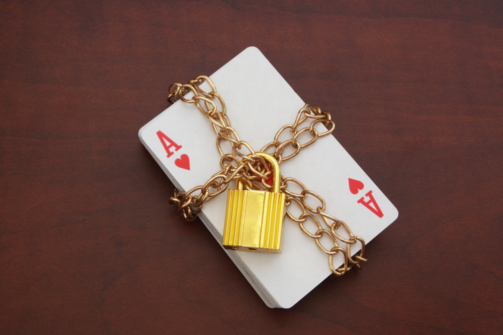 A deck of cards within a golden chain with a lock on it