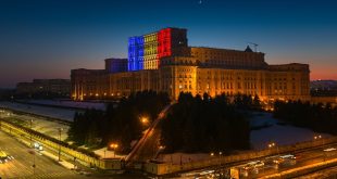The Romanian Parliament building lit up with the national flag