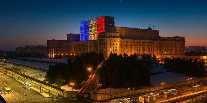 The Romanian Parliament building lit up with the national flag