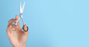 A hand holding open scissors