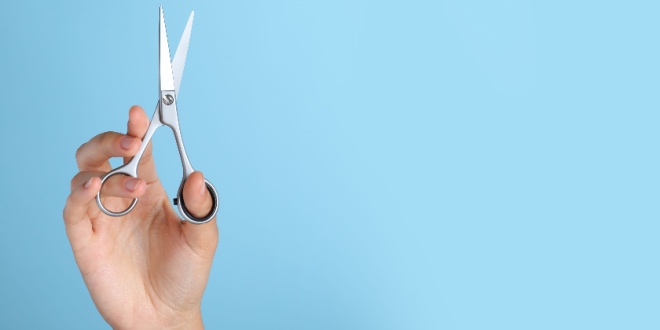 A hand holding open scissors