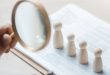 four figures under magnifying glass