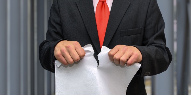 A man in a suit ripping a contract