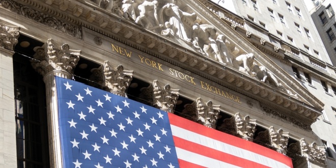 The New York Stock Exchange with a US flag in front, symbolising US predictions space which Flutter and Allwyn now have a big stake in