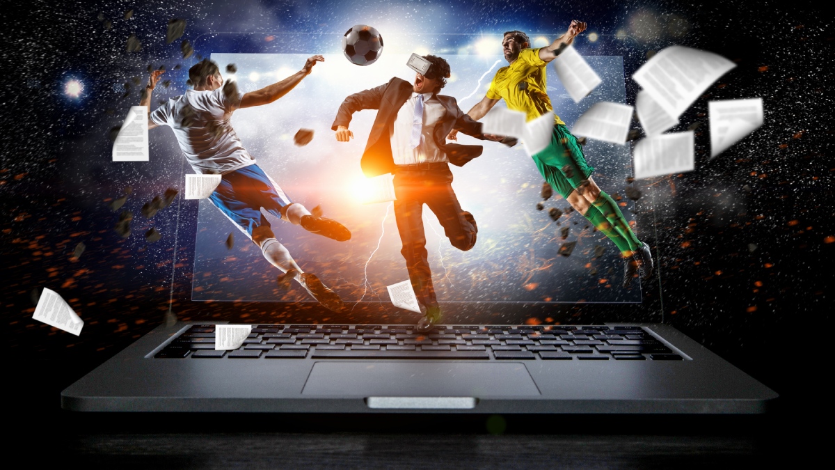 Figures play football out of a laptop screen, representing esoccer.