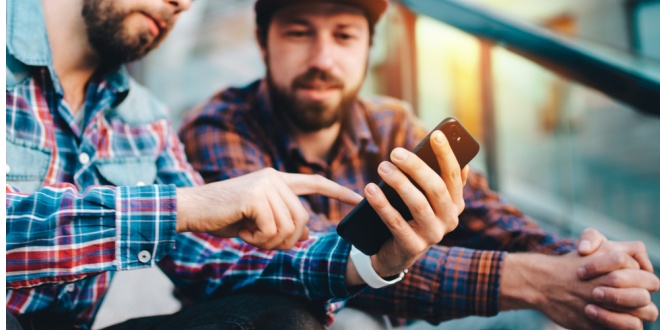 Man showing phone to friend, reperesenting data from Gambling Commission on black market