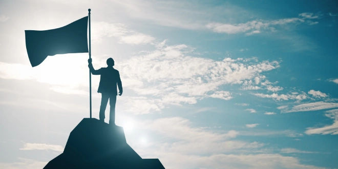 A man holding a flag at a mountain top, illustrating LSports' success.
