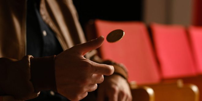 A man tossing a coin, symbolising Super Group and Betway slipping a loss into a profit in Q2 2026