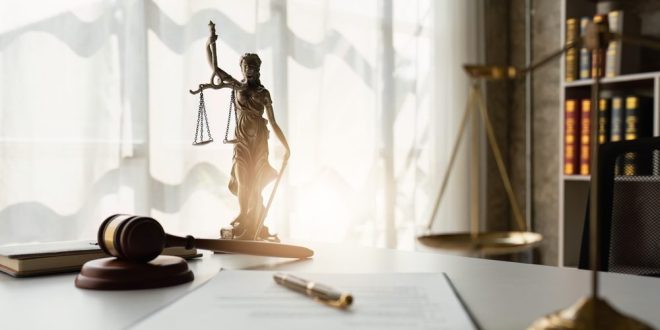 Scales of justice and clipboard and pen on a table, symbolising the kind of legal consultation ex-Entain General Counsel Simon Zinger is moving into